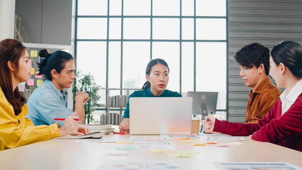 Team discussing a project around a laptop in a meeting room