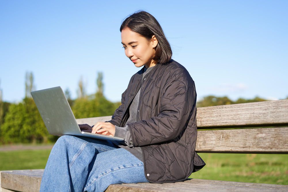 Woman using a laptop while seated outdoors