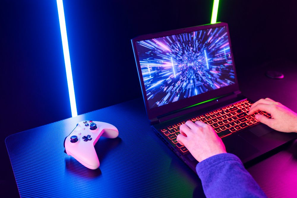 Person playing a game on a laptop beside a game controller