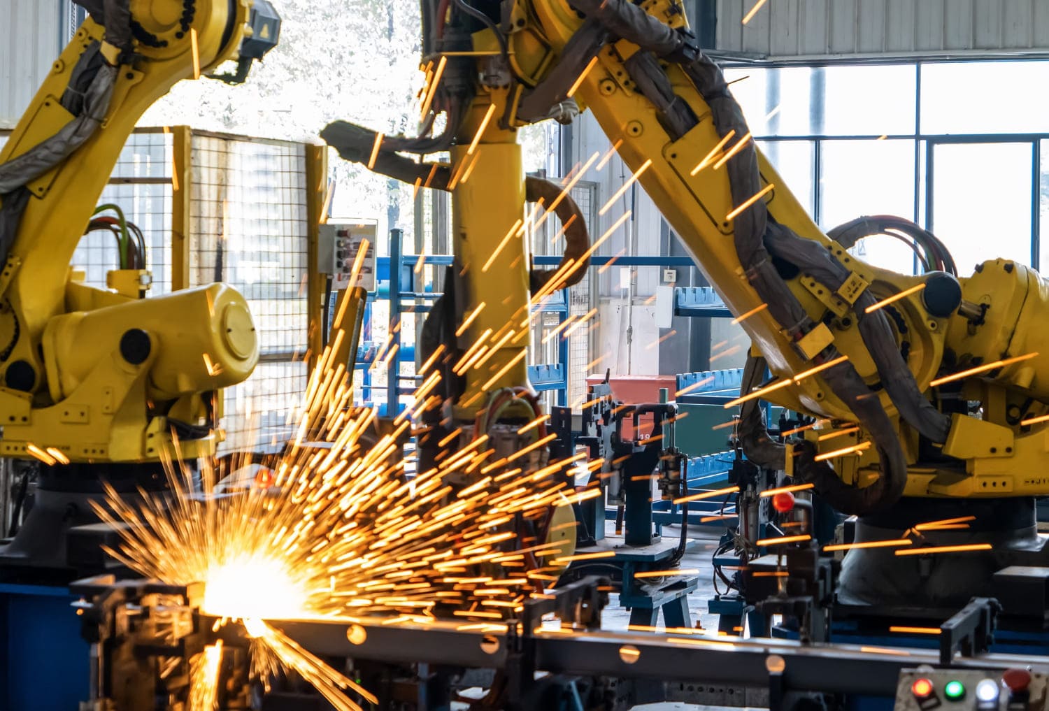 Industrial robotic arms welding metal with bright sparks