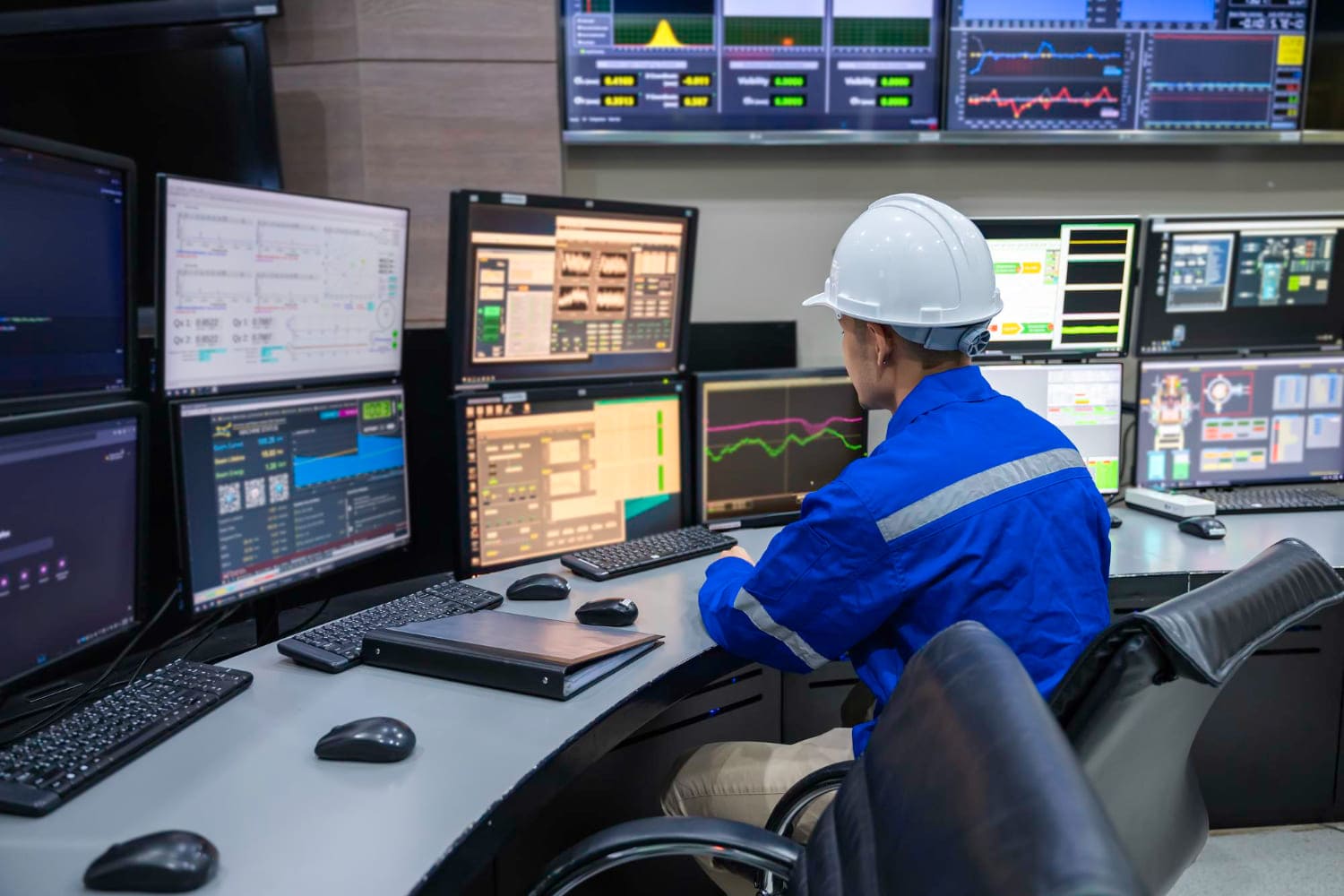 Operator at a control desk with industrial monitoring displays
