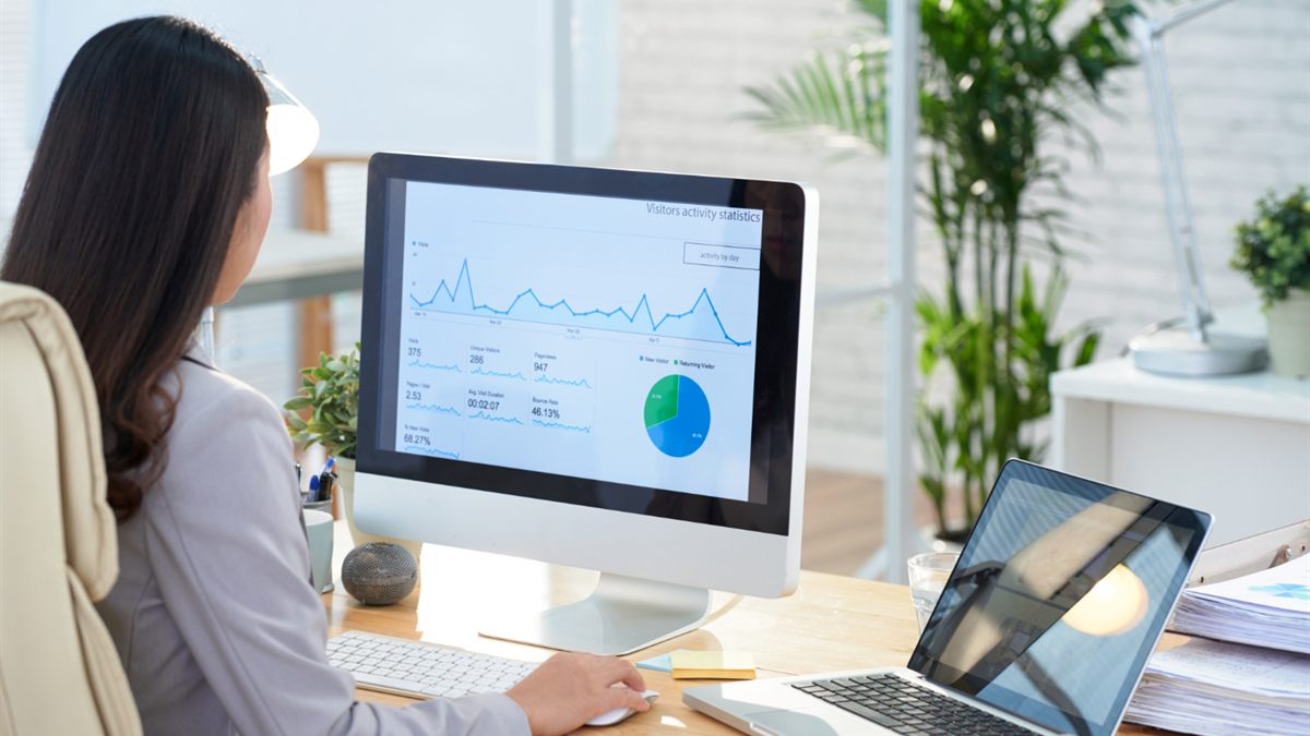 Person reviewing line and pie charts on a desktop monitor
