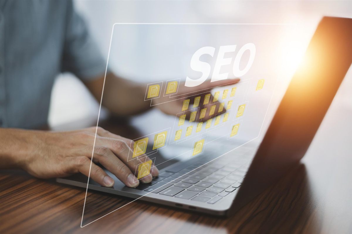 Person typing on a laptop with an SEO graphic overlay