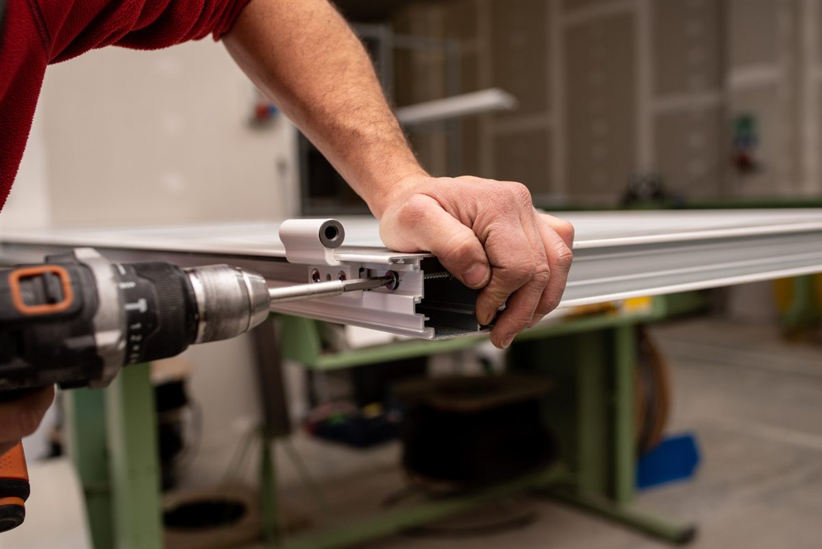 Worker fastening hardware to a window frame with a drill
